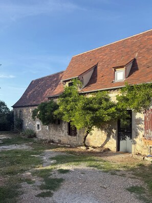 Ein Gebäude aus Stein mit einem geneigten Dach, einem kleinen Fenster und einer Tür.