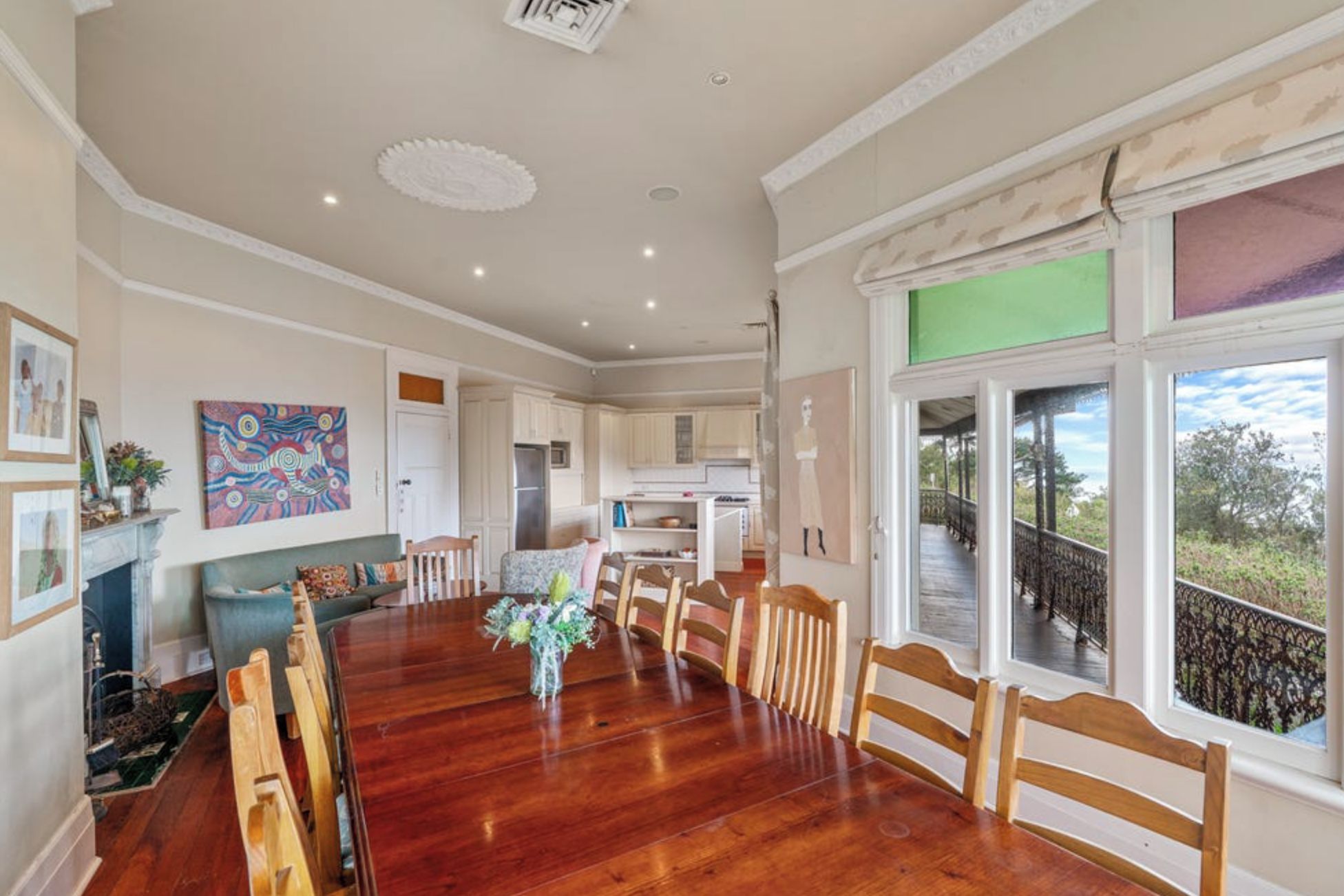 Uma sala de jantar ampla, com mesa e cadeiras de madeira, lareira e vista para o exterior.