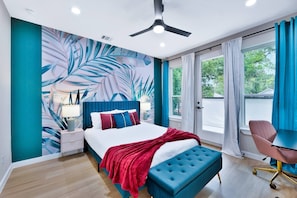 A modern bedroom with a large bed, a ceiling fan, a window with curtains, and a view of greenery outside. - Luxe Living in the heart of Dallas (Dallas)