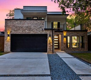 A modern two-story house with a brick facade, a garage, and a well-lit entrance. - Luxe Living in the heart of Dallas (Dallas)