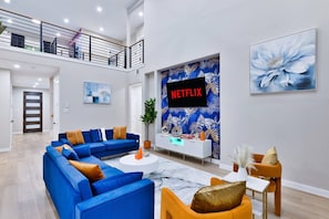 A modern living room with a sectional sofa, a coffee table, and a TV mounted on a wall with a 'NETFLIX' sign. - Luxe Living in the heart of Dallas (Dallas)