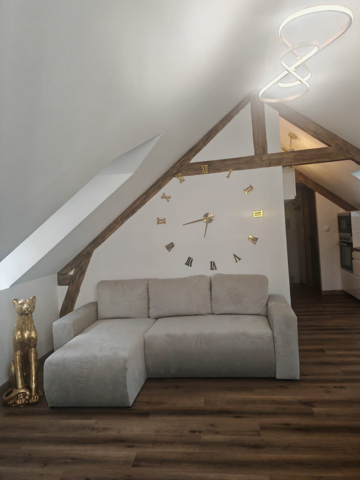 A loft-style room with a sloped ceiling, a sofa, a bear sculpture, and a wall clock.