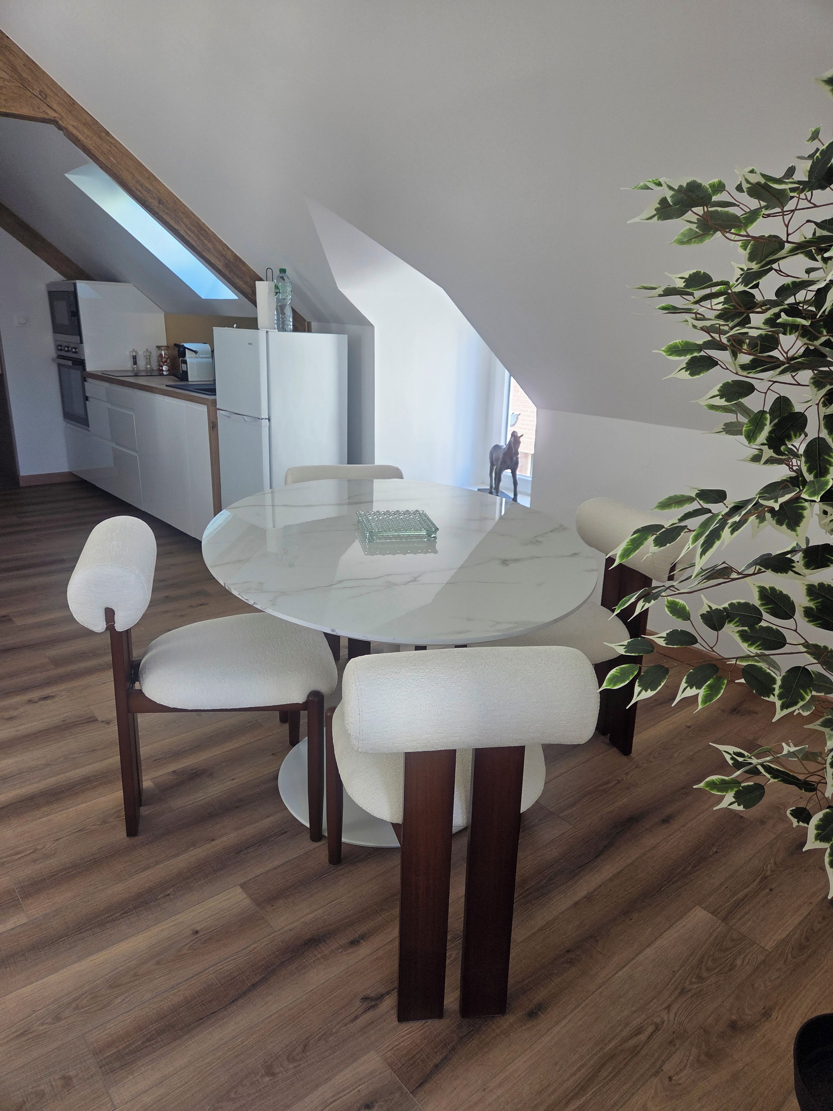 Un espace repas moderne avec une table ronde, des chaises rembourrées et un plancher en bois.