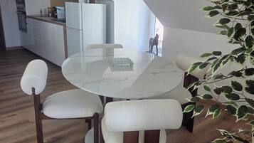Un espace repas moderne avec une table ronde, des chaises rembourrées et un plancher en bois.
