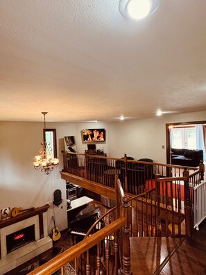 A spacious living area with a fireplace, a piano, a television, and a staircase leading to an upper level. - Elegant 5,000 Sq Ft Estate on 3 Acres, Pool&Jacuzzi. 10 min from Downtown Indy! (Indianapolis)