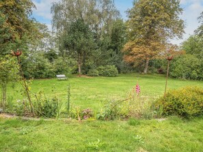 A grassy garden with a bench, trees, and various plants. - 5 Person Holiday Home in Laeso (Læsø)