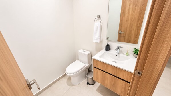 Une salle de bain moderne avec des toilettes, un lavabo et un miroir.