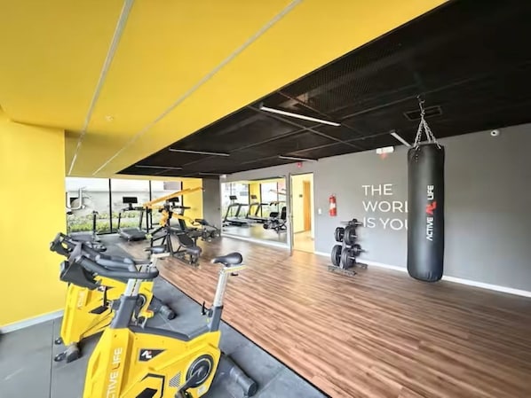A gym with stationary bikes, a punching bag, and a motivational quote on the wall.