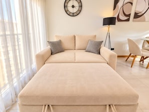 A modern living room with a sofa, a floor lamp, and artwork on the wall.
