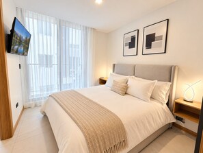 A modern hotel room with a large bed, a TV mounted on the wall, and a window with sheer curtains. - Stylish Suite in La Carolina, Parking + Gym (Quito)