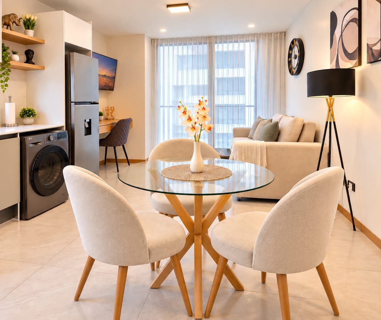 Una cocina moderna con lavadora integrada, un comedor con mesa de vidrio y cuatro sillas, y una sala de estar con sofá y lámpara de pie.