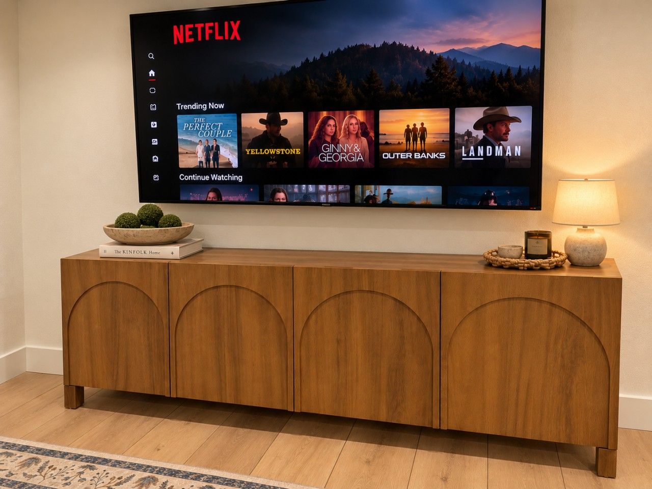 A flat-screen TV mounted on a wall displaying a Netflix interface with various show options.
