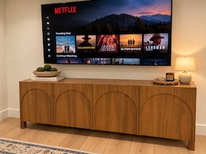 Una TV a schermo piatto montata a parete mostra l'interfaccia di Netflix con diverse opzioni di programmazione.