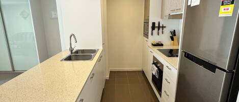 A modern kitchen with a stainless steel refrigerator, a sink, and a countertop.