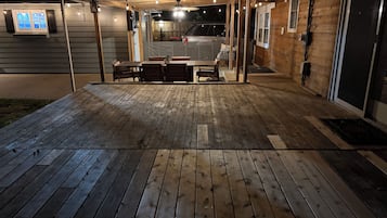 A wooden deck with string lights, a covered seating area, and a garage entrance.