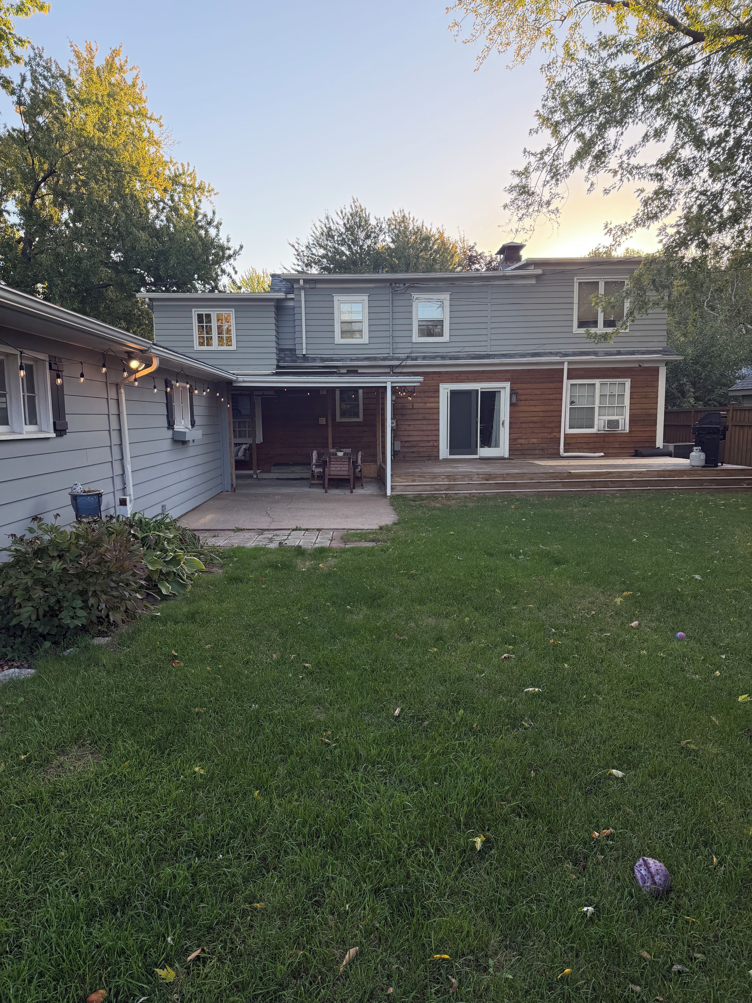 A two-story house with a covered patio and a grassy backyard.