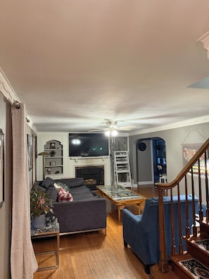 Una sala de estar con sofá, mesa de centro, televisión y chimenea.