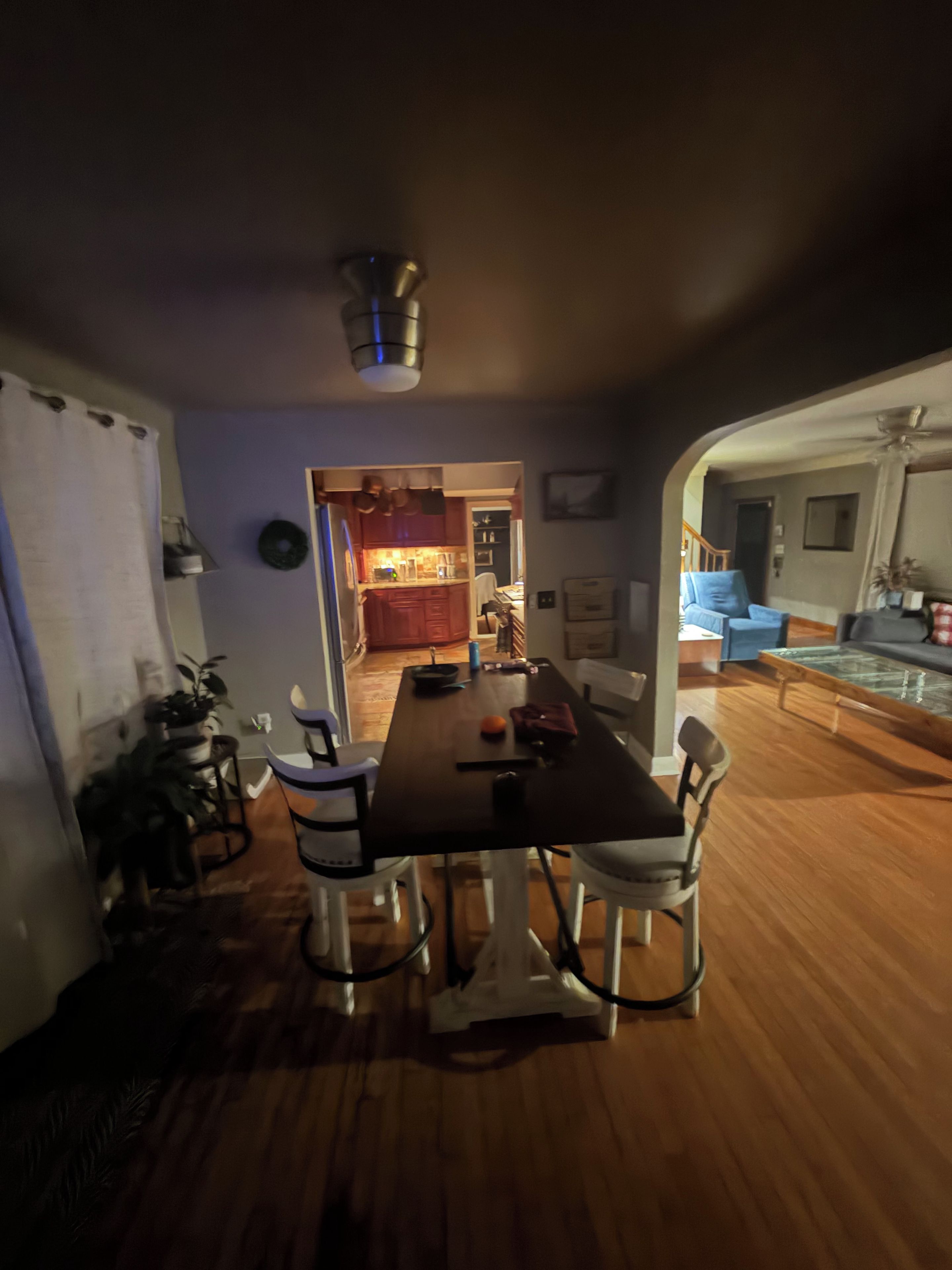 A dining area with a table and chairs, a kitchen in the background, and a living area with a sofa and a coffee table.