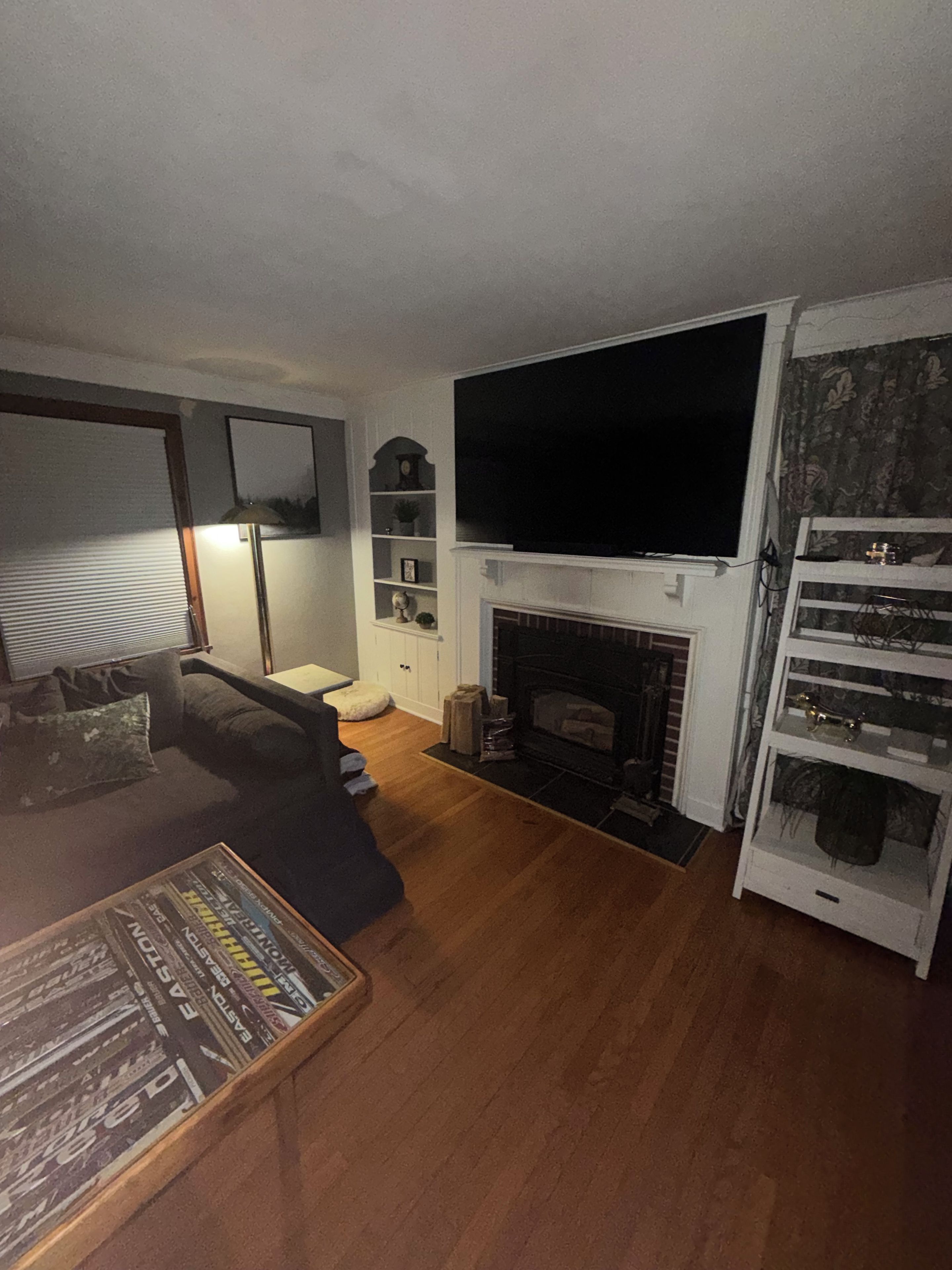 Una sala de estar con chimenea, un sofá, un televisor y una estantería.
