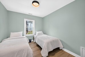 Ein Zimmer mit zwei Betten, einem Fenster und einer Lampe.