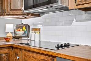 A kitchen with wooden cabinets, a stainless steel range hood, white tiled backsplash, and a wooden countertop. - Wildwood Acres | Peaceful 10-Acre Wooded Retreat (Trafalgar)