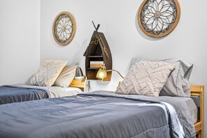 A bedroom with two beds, a nightstand, a lamp, and decorative wall art. - Wildwood Acres | Peaceful 10-Acre Wooded Retreat (Trafalgar)