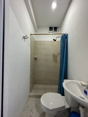 Ein kleines Badezimmer mit Dusche, Toilette und Waschbecken.