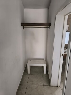 Um corredor estreito com um banco branco e uma prateleira.