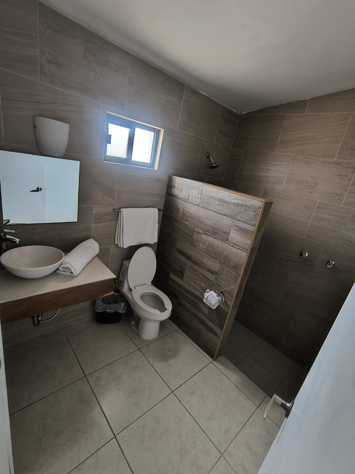 Un baño moderno con inodoro, lavamanos y ducha.