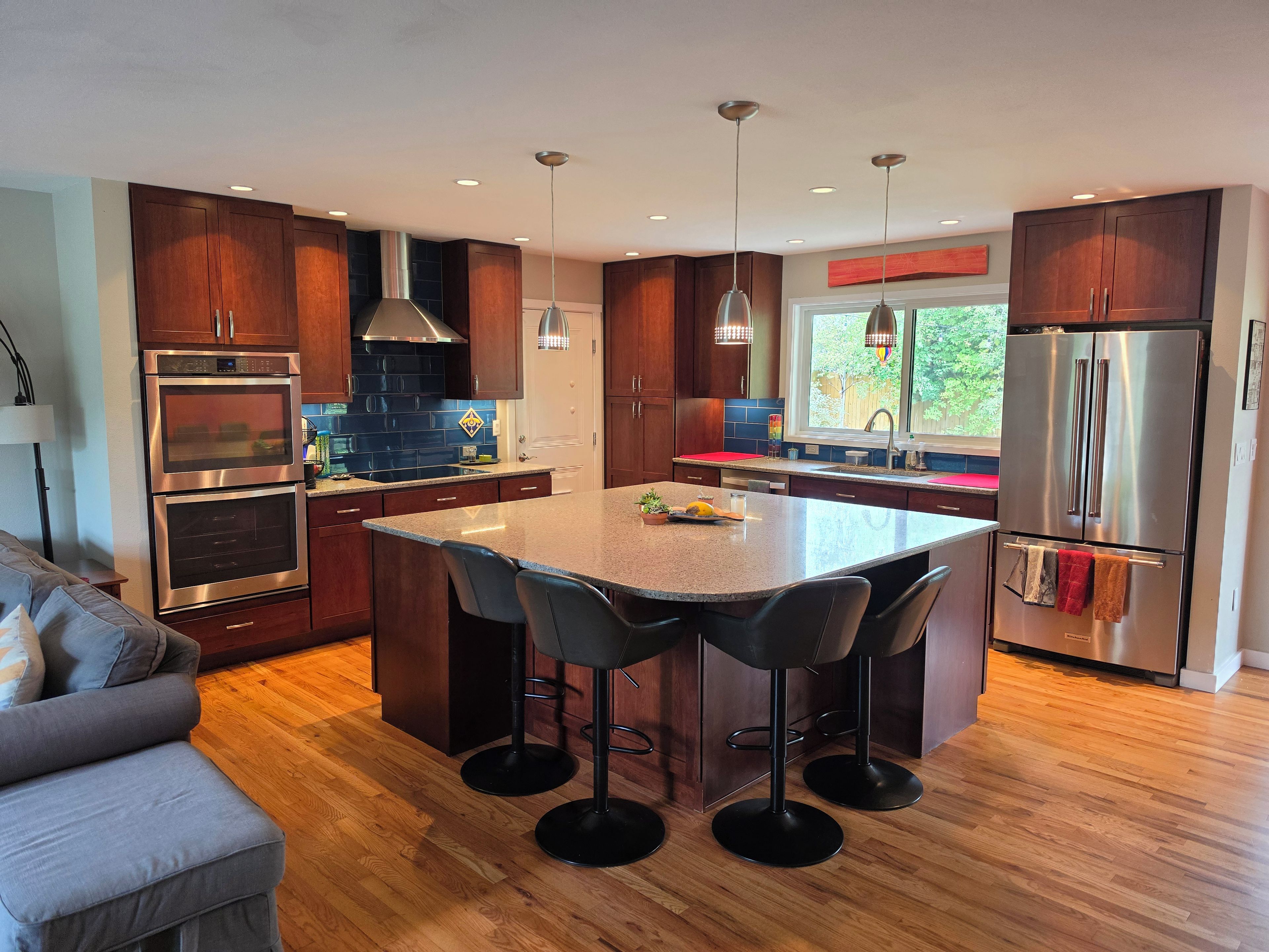 Cocina moderna con armarios de madera, electrodomésticos de acero inoxidable y una isla central con taburetes de bar.