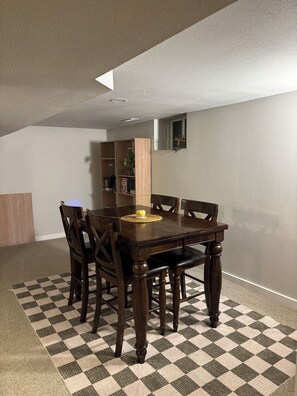 A dining area with a wooden table and chairs, a checkered rug, and a bookshelf against the wall. - Sundance 6BR  Prime Location & Space (Boulder)