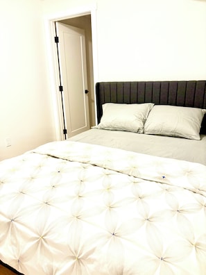 Ein Schlafzimmer mit einem Bett, zwei Kissen, einer Tür und einer Wand.