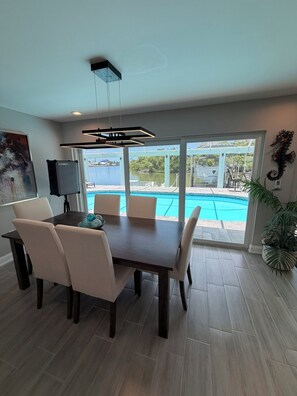 A dining area with a view of a swimming pool and a boat. - Amazing View Gulf Access 2100 Sq Ft House 3-BD Pool, Boat Lift 2 Min To Gulf Bay (Fort Myers Beach)