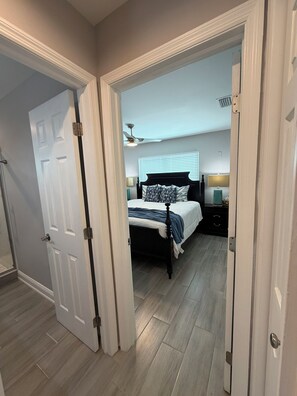 A bedroom with a bed, bedside tables, a ceiling fan, and a window with blinds. - Amazing View Gulf Access 2100 Sq Ft House 3-BD Pool, Boat Lift 2 Min To Gulf Bay (Fort Myers Beach)