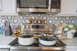 A kitchen with a stainless steel stove, a microwave above it, and a patterned backsplash. - Sunlit 2BR Near Revere Beach & Blue Line to Boston (Revere)