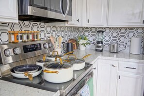 A modern kitchen with stainless steel appliances, a hexagonal patterned backsplash, and a variety of cooking utensils. - Sunlit 2BR Near Revere Beach & Blue Line to Boston (Revere)