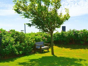 A bench in a garden with a tree and flowering bushes. - "haus Parkstrasse" - Apt. 01 (Wyk auf Foehr)