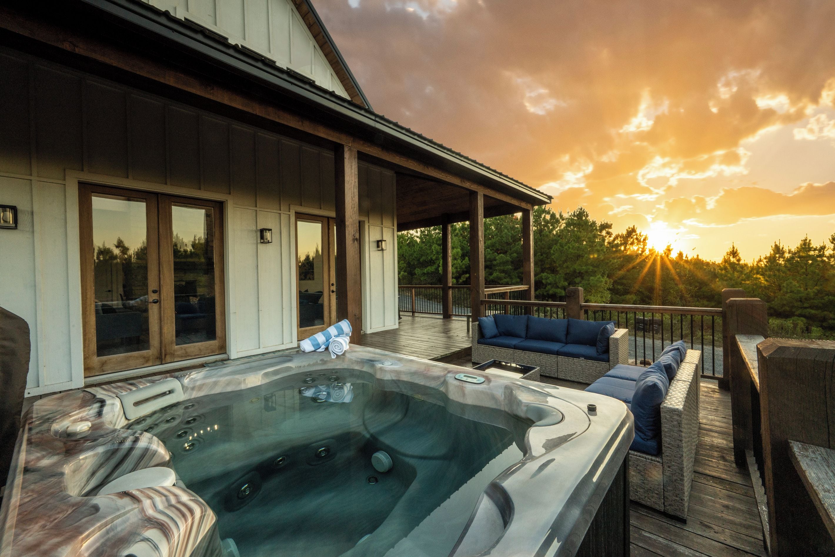 Un jacuzzi en una terraza de madera con un atardecer al fondo.