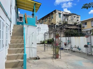 A courtyard with a staircase, a metal structure with plants, and a building with a white facade. - Salsa Paradise 1BR in Walkable Santurce (Santurce)
