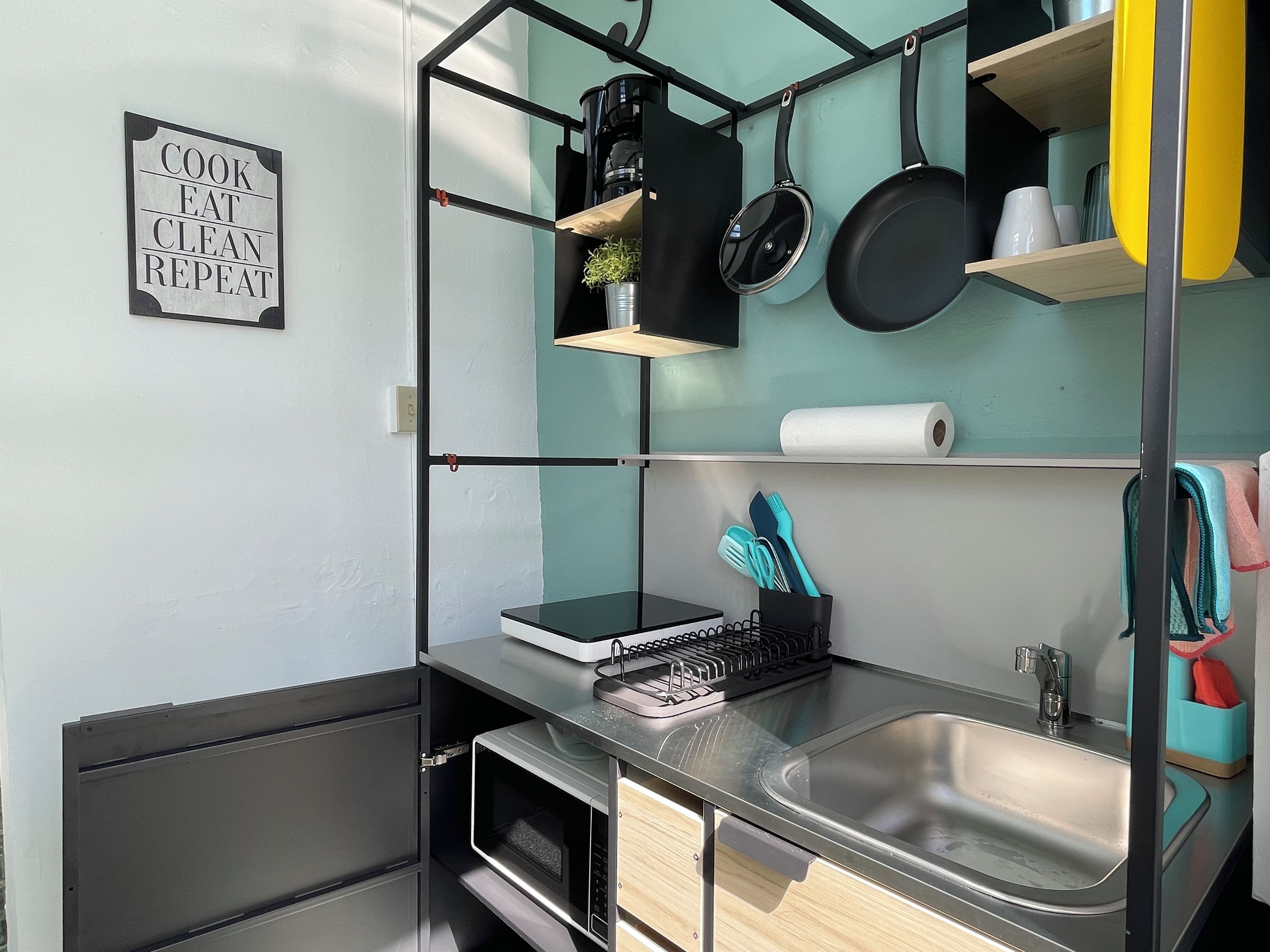 A compact kitchen with a built-in microwave, a sink, and a coffee maker.