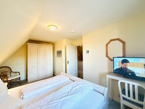 A hotel room with a bed, a television, a wardrobe, and a chair. - Rectory Courtyard - House Section 4 (Wrixum)