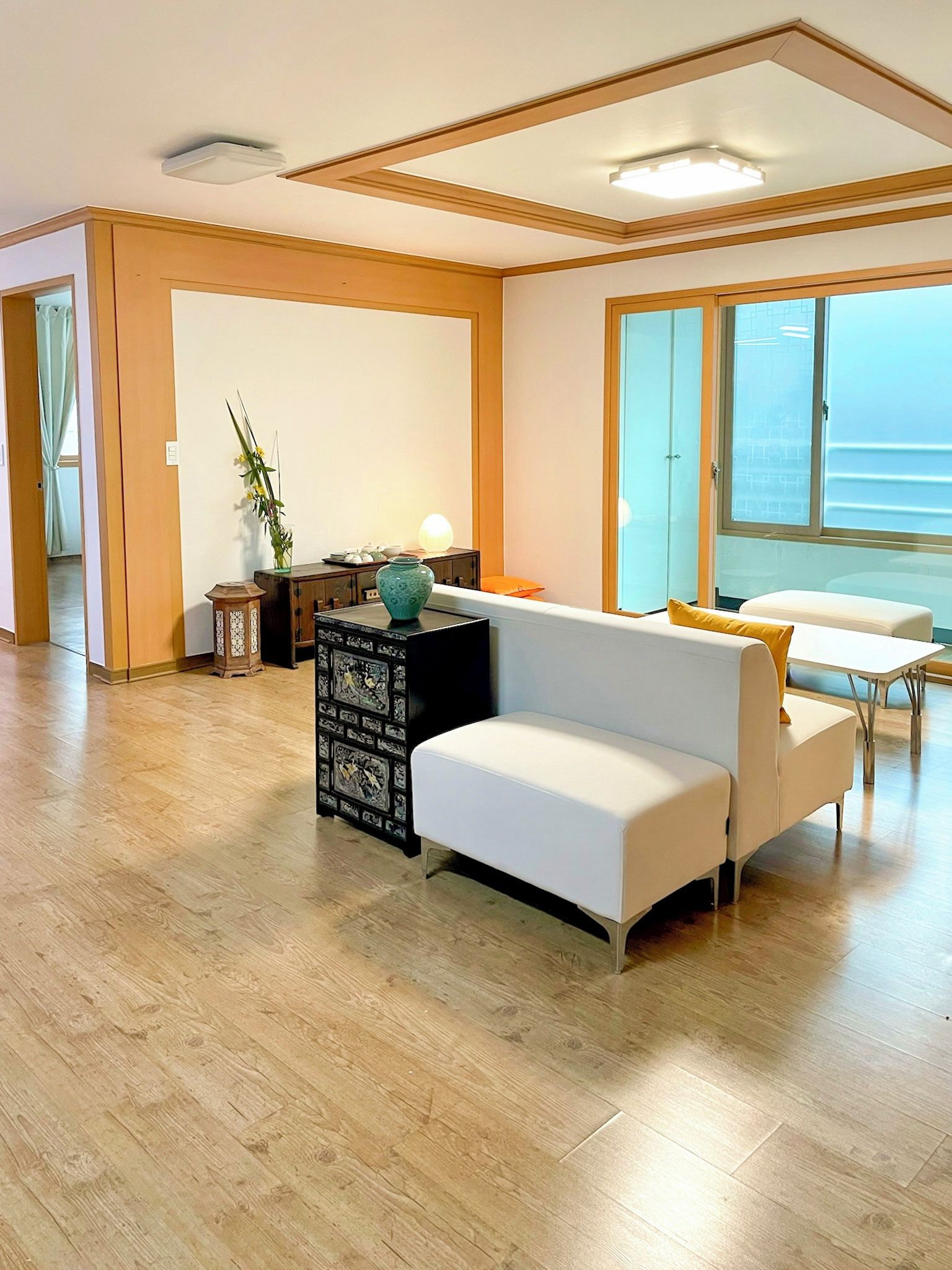 A spacious living area with a white sofa, a small side table, and a decorative vase.