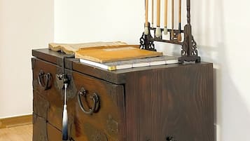 A wooden dresser with multiple drawers and a small shelf, a framed picture on the wall, and a traditional Chinese instrument on top.