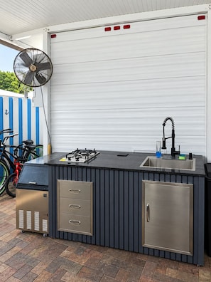 An outdoor kitchen area with a gas stove, sink, and storage cabinets. - Turtle Nest in the Keys - Cozy RV Retreat in Key Largo - Golf Cart Included (Key Largo)