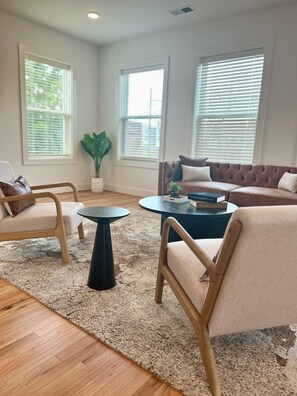 A living room with a brown leather sofa, two armchairs, a coffee table, and a potted plant. - Spacious 3BR Downtown Near VCU With Private Rooftop Patio & Free Parking (Richmond)
