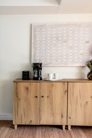 Un meuble en bois sur lequel sont posés une machine à café et deux tasses blanches.