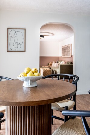 A dining area with a round wooden table, a white bowl with lemons, and a modern chair design. - Spacious 2BR Near Colorado School of Mines | Workspaces + Patio (Golden)