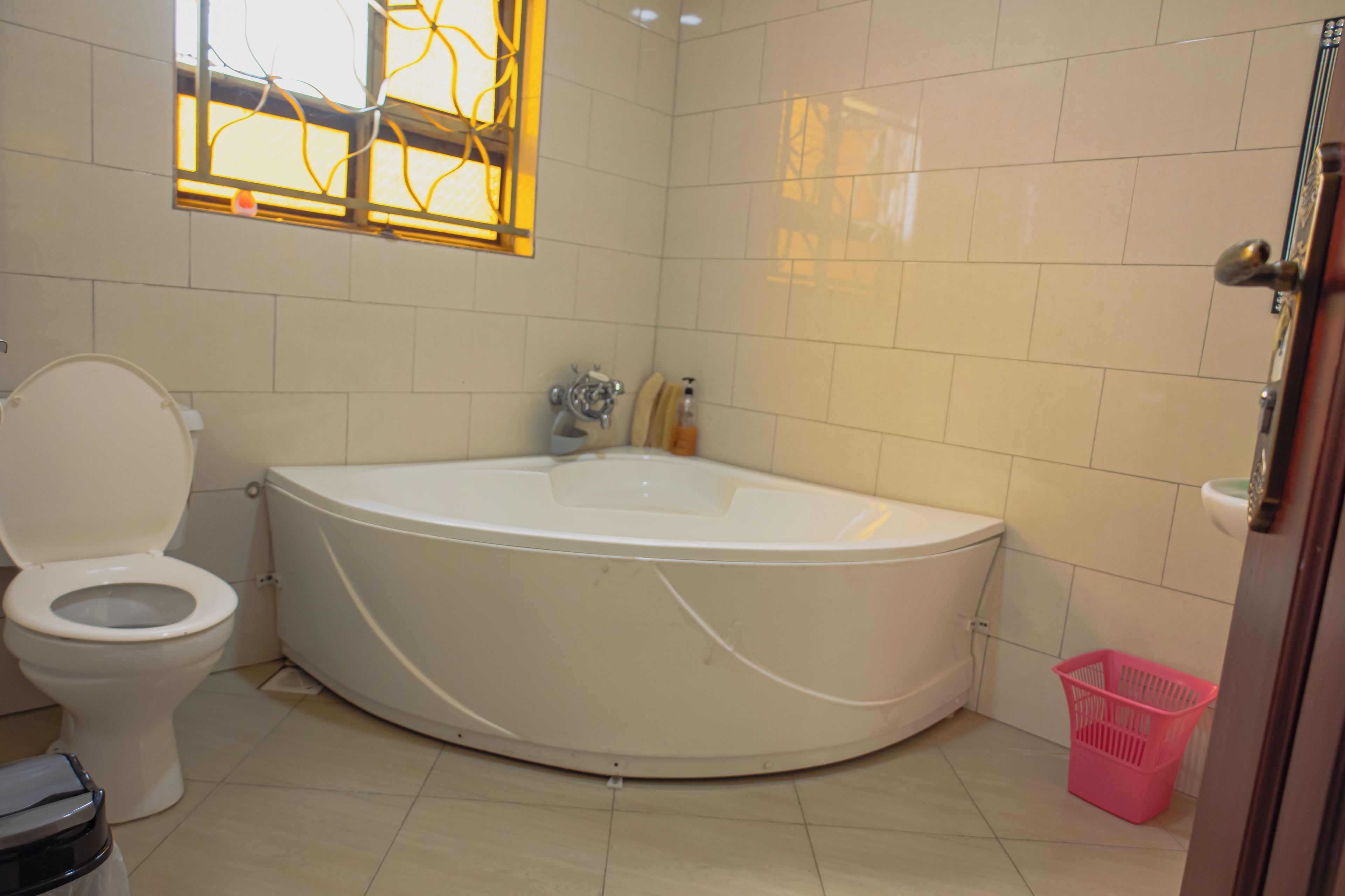 A bathroom with a toilet, a bathtub, and a window with a decorative design.