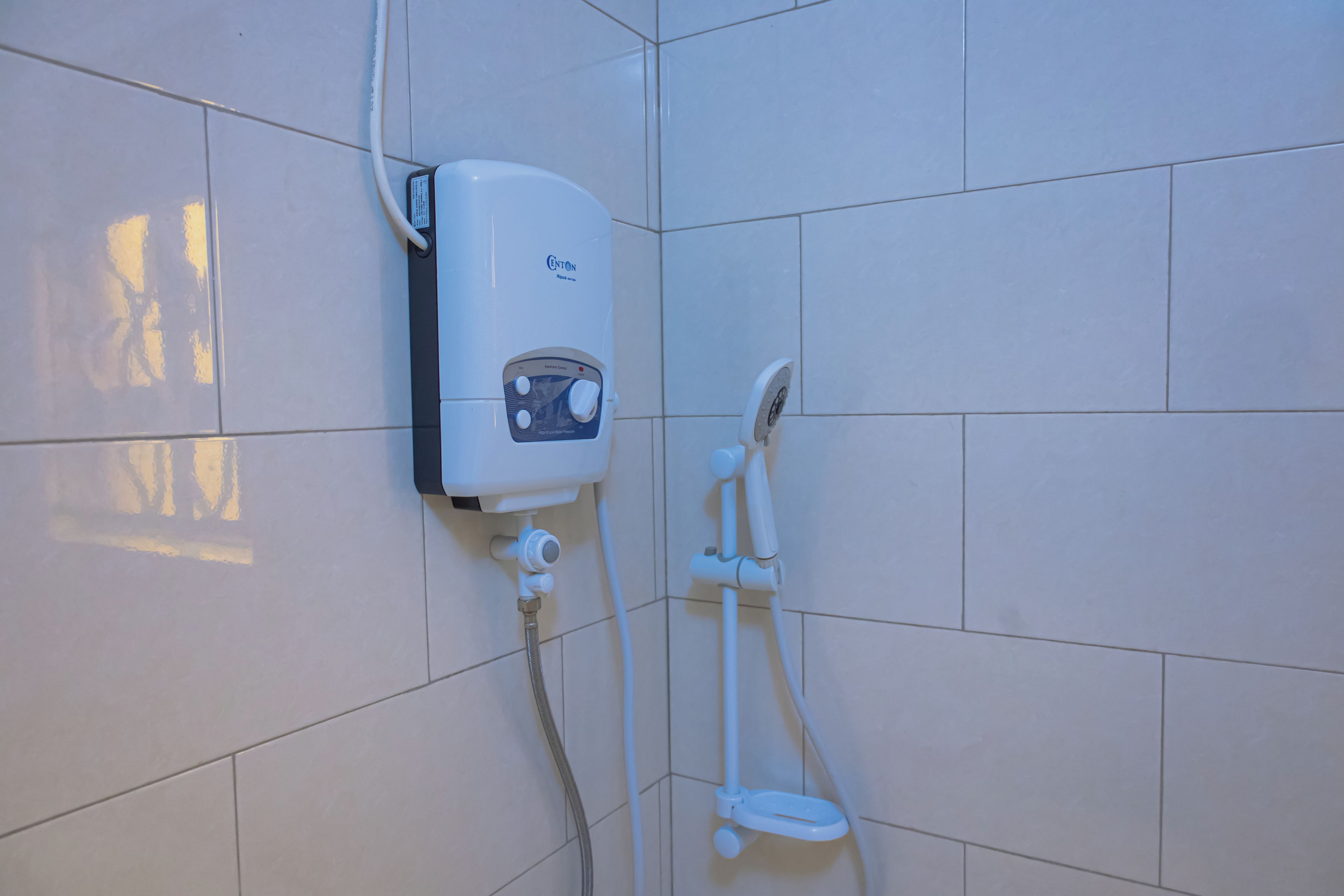 Een badkamer met een wandgeplaatst boiler, een handdouche en een handwasbak.