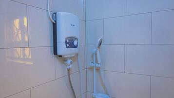 Een badkamer met een wandgeplaatst boiler, een handdouche en een handwasbak.